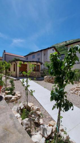 a garden with trees and rocks in front of a building at Apartments Kapetanovina in Mostar