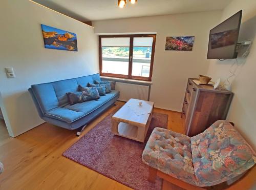 a living room with a blue couch and a chair at Aira Apart in Nauders