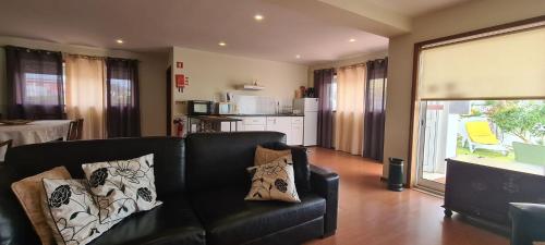a living room with a black leather couch with pillows at Casa Lagoa Verde in Esmoriz