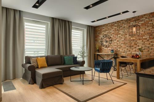 a living room with a couch and a brick wall at Zentrum Apartament IMPERO z Parkingiem in Poznań