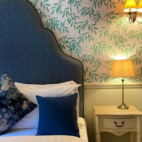 a bed with a blue pillow next to a table with a lamp at Holdsworth House Hotel in Halifax