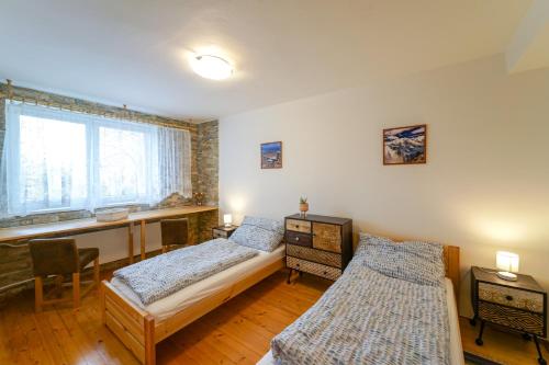 1 dormitorio con 2 camas, escritorio y ventana en Víkendový byt v Tatranskej Lomnici, en Tatranská Lomnica