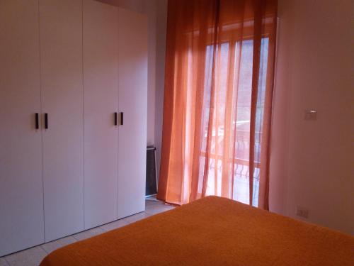 a bedroom with a bed and a window with orange curtains at Casa Fronte Gole Alcantara in Motta Camastra