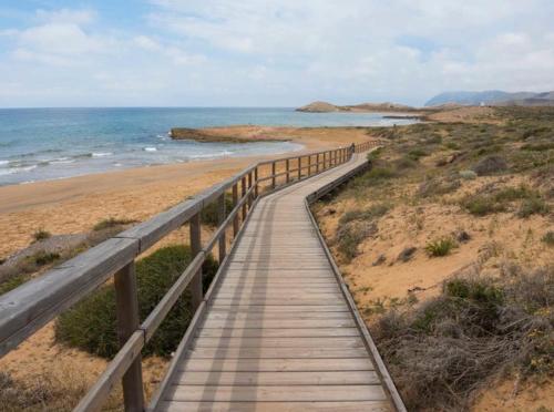 a wooden boardwalk leading to a beach with the ocean at Hotel Restaurante Campomar in Cartagena