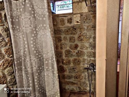 a shower curtain in front of a stone wall at Angelic in the mountains in Kaisárion