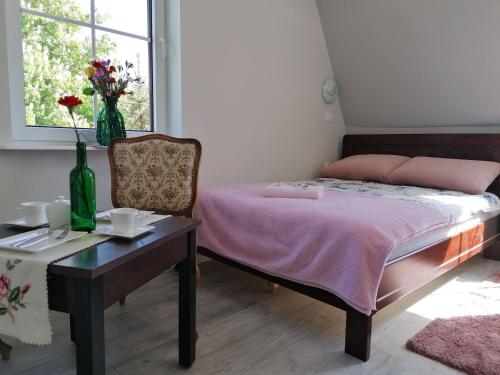 a bedroom with a bed and a table and a window at Pokoje Alicja Ustka in Ustka