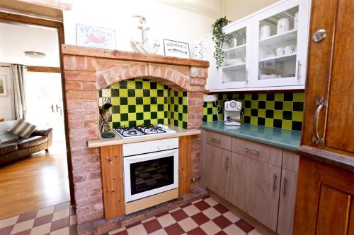 a kitchen with a stove and a brick fireplace at Mackerel Cottage in Budleigh Salterton