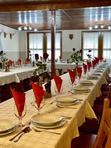 a long table with red glasses and plates on it at Tapolca Fogadó in Miskolctapolca