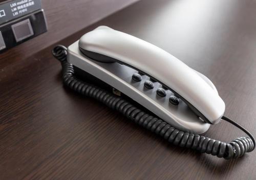 a white phone sitting on a wooden table at APA Hotel Keisei Narita Ekimae in Narita