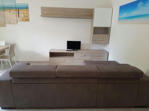 uma sala de estar com um sofá e uma secretária com um computador portátil em Blu Baita em La Maddalena