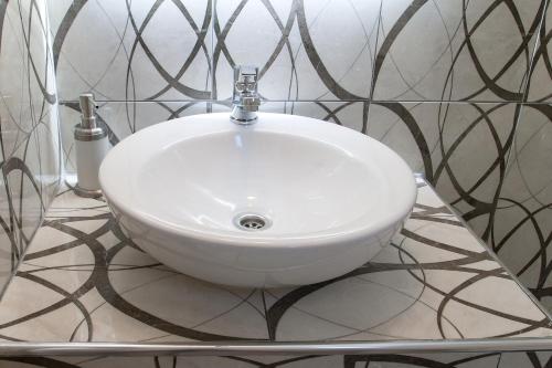 a white sink in a bathroom with black and white tiles at 3 Goddesses' studios in Koukounaries