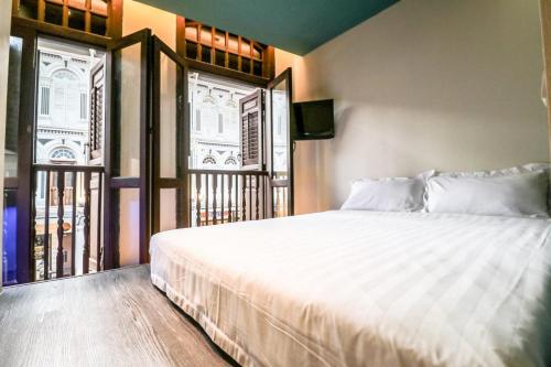 a bedroom with a large white bed and a window at Hotel Calmo Chinatown in Singapore