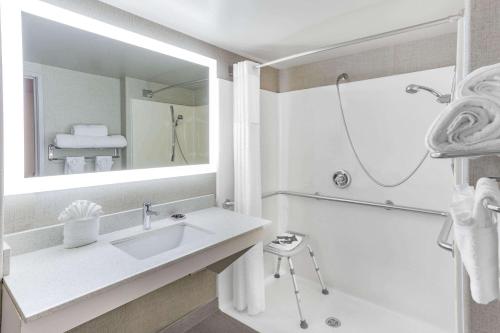 a white bathroom with a sink and a shower at Wingate by Wyndham Tinley Park in Tinley Park
