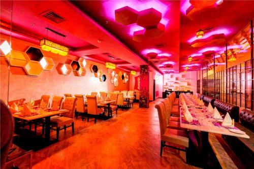 a restaurant with tables and chairs and purple lights at Ramada Neemrana in Neemrana