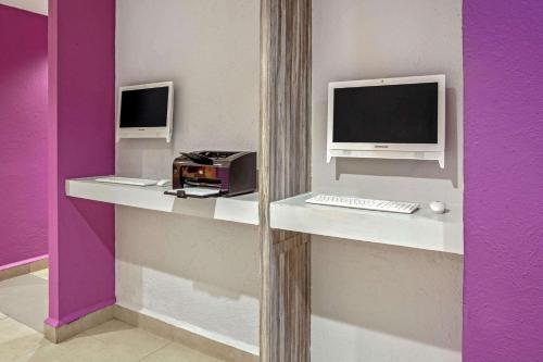 a desk with two computer monitors and a keyboard at CHN Hotel Monterrey Centro, Trademark Collection by Wyndham in Monterrey