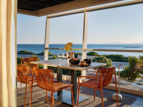 a table and chairs on a patio with a view of the ocean at 3 Olive Trees in Anavissos