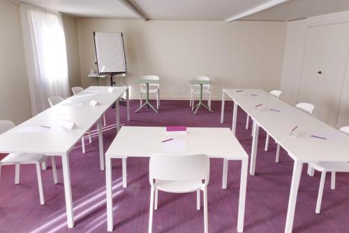 a classroom with white tables and white chairs at Mercure Perpignan Centre in Perpignan