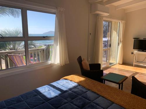 a bedroom with a bed and a large window at Driftwood Beachfront Accommodation, Cable Bay, Owhetu in Coopers Beach