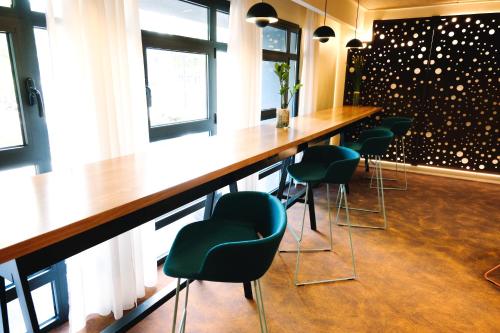 a bar with green chairs and a long counter at Mercure Perpignan Centre in Perpignan