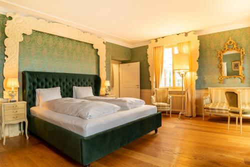a bedroom with a large bed with a green headboard at Hotel Porto Sofie Gottlieben in Gottlieben