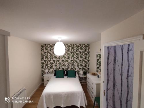 a bedroom with a white bed with green pillows at Casa Pepa in Corcubión