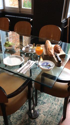 einen Glastisch mit Essen darauf mit zwei Stühlen in der Unterkunft Maison d'Hôtes La Lumière de Migou in Beaumont-de-Lomagne