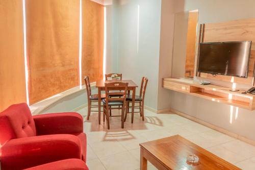 a living room with a table and chairs and a television at Baden Hotel Suites in Amman