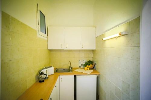 Una pequeña cocina con gabinetes blancos y un fregadero. en Christina studios, en Laganas