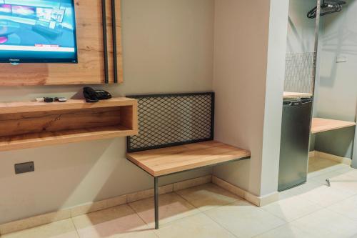 a room with a bench and a tv on a wall at Baden Hotel Suites in Amman