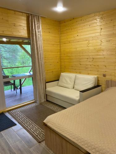 a room with a bed and a couch and a window at Touristic complex Taiezhnik in Manzherok