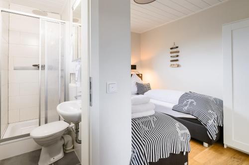 a white bathroom with a bed and a sink at Welle und Woge in Dagebüll