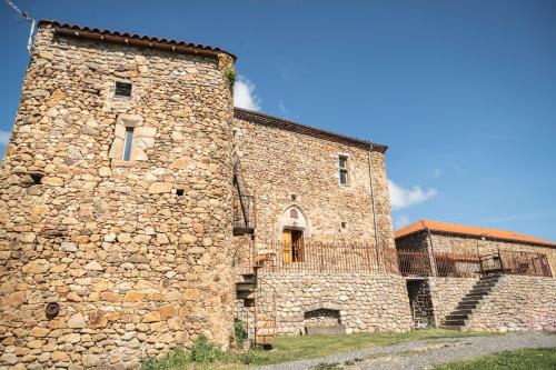 a large stone building with a stone wall at le Donjon de la Reine Margot in Beaumont