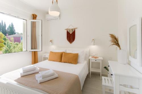 a white bedroom with a bed and a desk at Casa Micallef Corfu in Kontokali