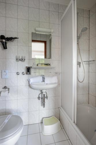 a white bathroom with a sink and a shower at Pension Louisa in Dagebüll