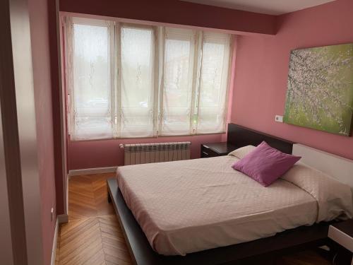 a bedroom with a bed with a pink wall at Garelly 2 in San Vicente de la Barquera