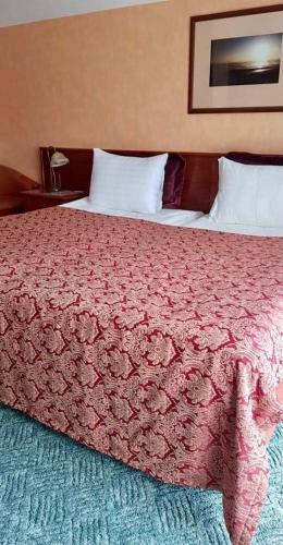 a bedroom with a large bed with a red comforter at Vila Florena Garden in Palanga