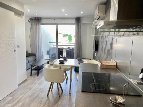 une cuisine et un salon avec une table et des chaises dans l'établissement L'HERMITAGE - Studio moderne - Piscine - Ascenseur - Quart Golf, à La Grande Motte