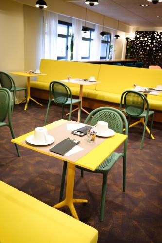 a cafeteria with yellow tables and chairs with hats on them at Mercure Perpignan Centre in Perpignan