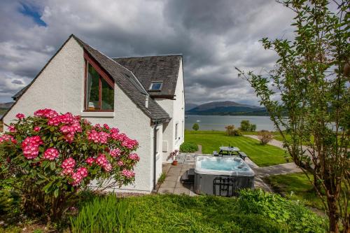 a white house with a hot tub and flowers at Seabank Lochside Farmhouse in Oban