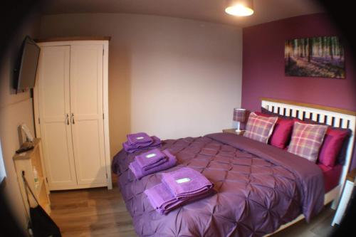 a bedroom with a purple bed with a suitcase on it at Immaculate 1 Bed Apartment in Pitlochry Scotland in Pitlochry