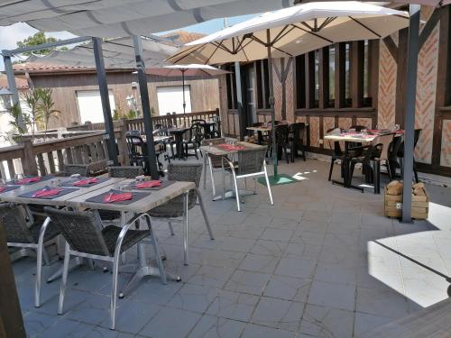 an outdoor patio with tables and chairs and umbrellas at Le Fair Play in Léon