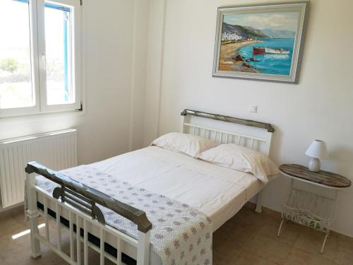 a bedroom with a bed and a painting on the wall at Paros Iliahtides Apartments near Golden Beach in Márpissa