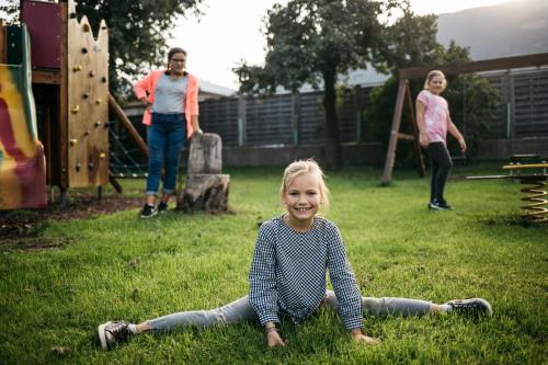a little girl sitting on the grass in the yard at Apparthaus & Chalets Hofer in Zell am Ziller