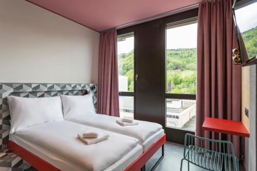 a hotel room with two beds and a window at MEININGER Hotel Zürich Greencity in Zurich
