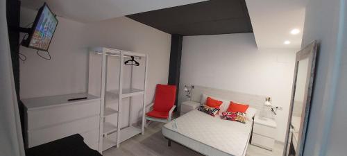 a small bedroom with a bed and a red chair at valencialoft in Valencia