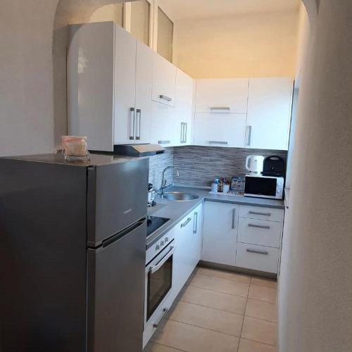 a kitchen with white cabinets and a stainless steel refrigerator at Apartment Fran in Sonković