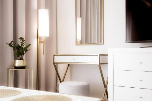 a white bedroom with a dressing table and a mirror at Maritime Residence in Międzyzdroje