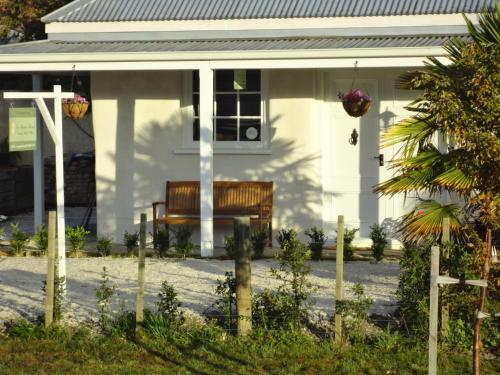 a white house with a bench in front of it at Woodstock Suite in Nelson