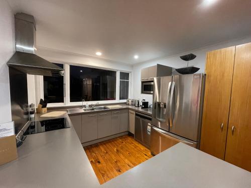 a large kitchen with stainless steel appliances and wood floors at Ocean Front East End Beach House in New Plymouth