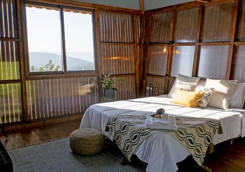 a bedroom with a bed in a room with windows at Cimo da Vinha - Nature Spot in Castelo de Paiva